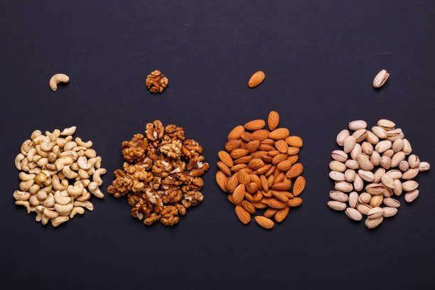 A colorful assortment of nuts and dry fruits including almonds, cashews, raisins, and pistachios displayed in bowls.