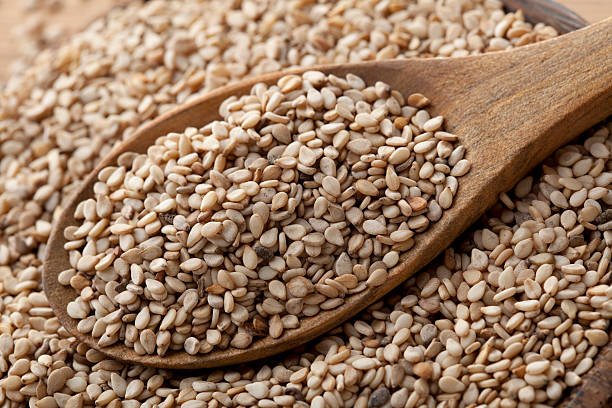 A close-up of sesame seeds and fresh sesame leaves, highlighting their tiny, oval shape and nutty appearance.