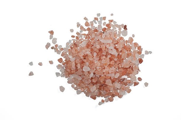 A small bowl of pink Himalayan salt crystals on a wooden surface.