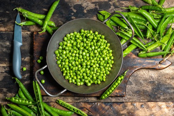 A bowl of fresh green peas in pods, showcasing their vibrant color and tender texture.