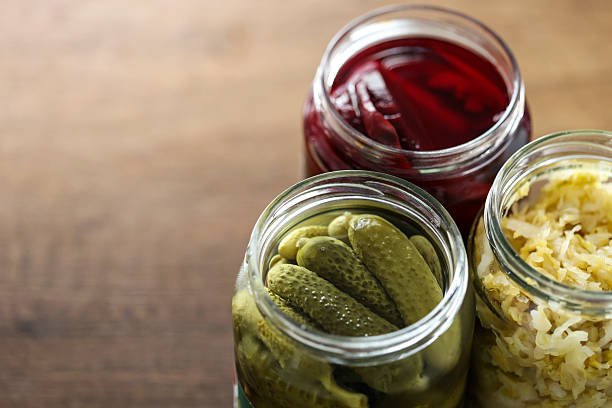 A bottle of apple cider vinegar with a glass of diluted vinegar for cooking.