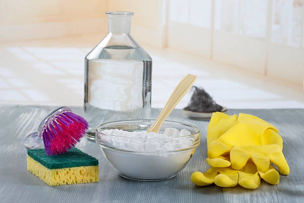 A spoonful of baking soda being sprinkled into a mixing bowl for baking.