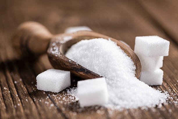 A bowl of white granulated sugar with a spoon ready for baking or cooking.