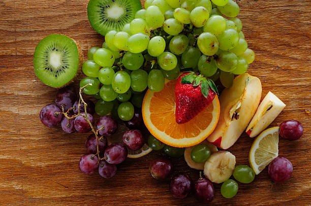 A colorful assortment of fresh fruits including apples, oranges, bananas, grapes, and berries displayed in a basket.