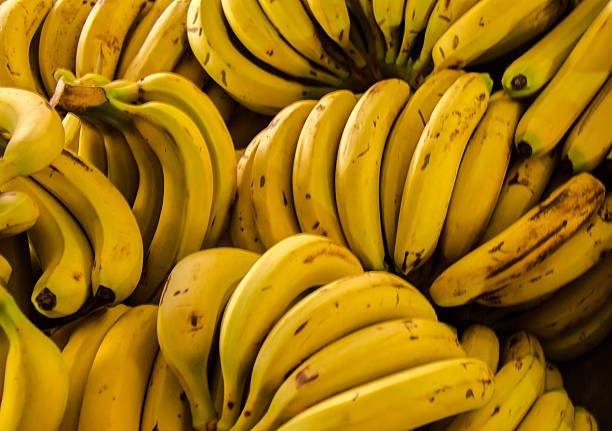 Ripe yellow bananas arranged in a bunch on a wooden table.
