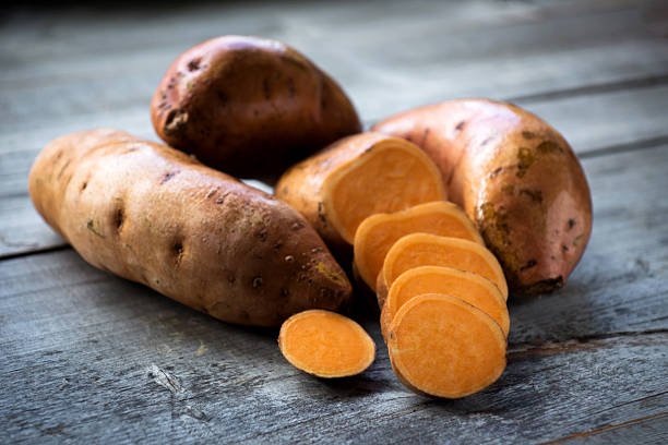 Freshly baked and sliced sweet potatoes showing their vibrant orange flesh.